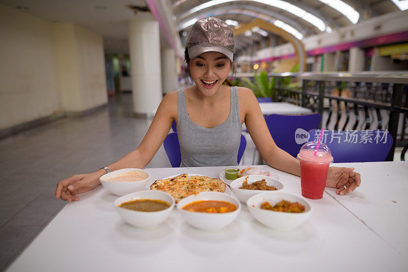 年轻美丽的亚洲女游客在餐厅享受印度美食的肖像