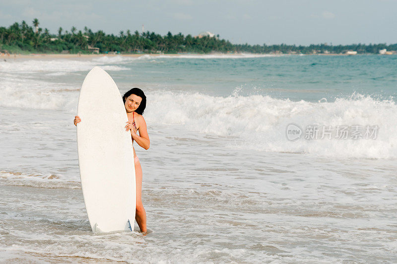 年轻的冲浪者站在海滩上拿着冲浪板。斯里兰卡。弥留的