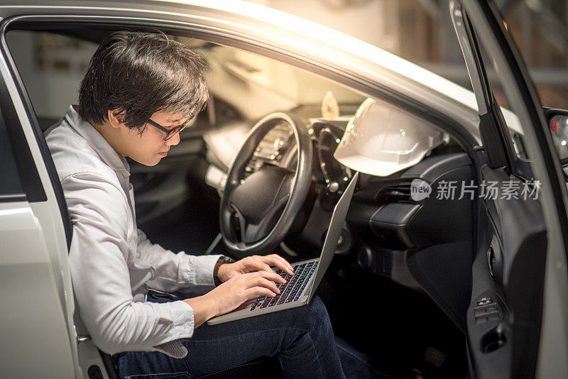 年轻的亚洲工程师或建筑师与笔记本电脑工作，而坐在他的车