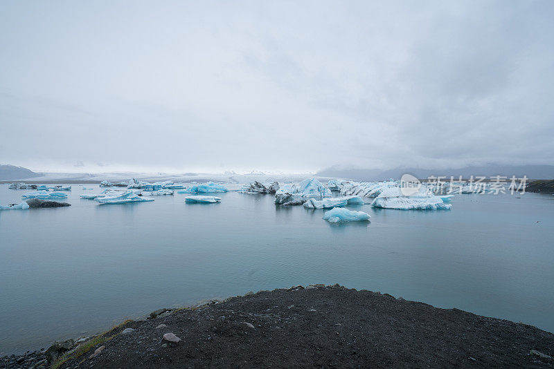 冰岛冰川泻湖的壮观景象与冰山漂浮在水上，阴天