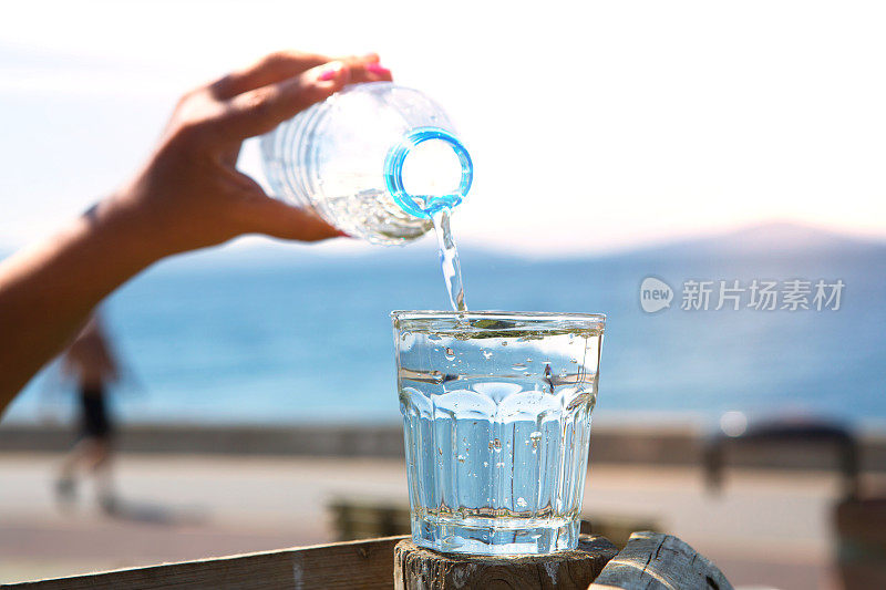 那只手正在把瓶子里的水倒在海滩上。