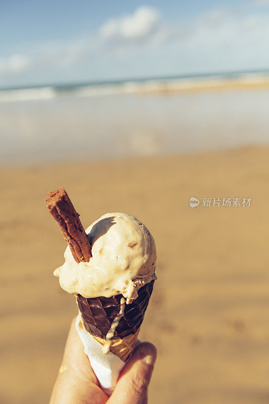 在一个阳光明媚的九月，康沃尔纽基菲斯特拉海滩的腌制焦糖冰淇淋蛋筒。