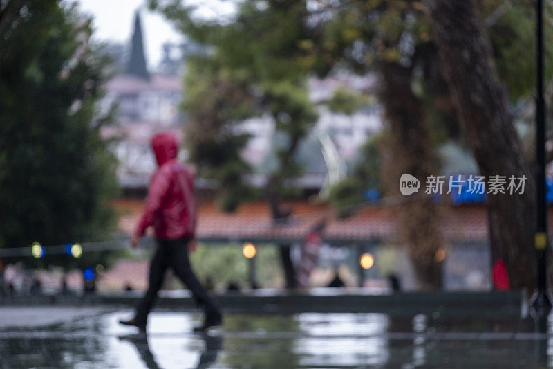 模糊的人们在雨中行走