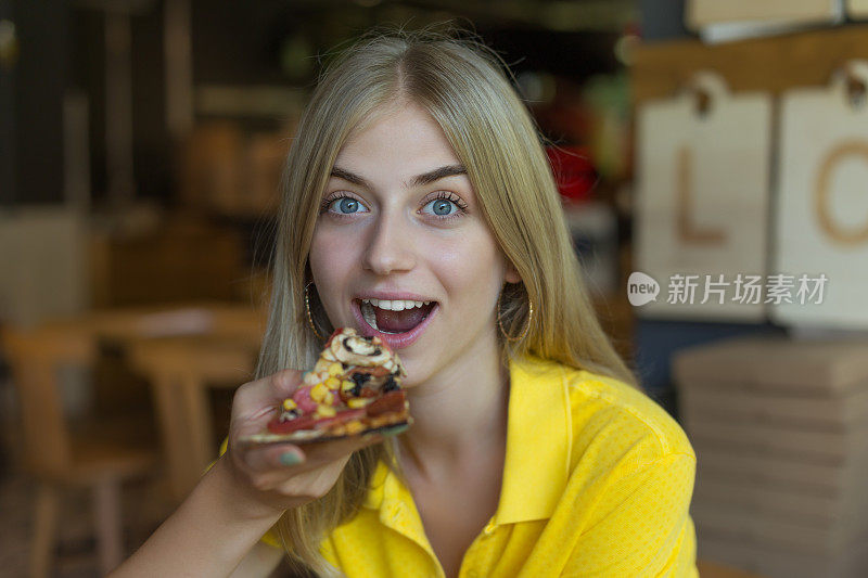 女人咬着一片披萨