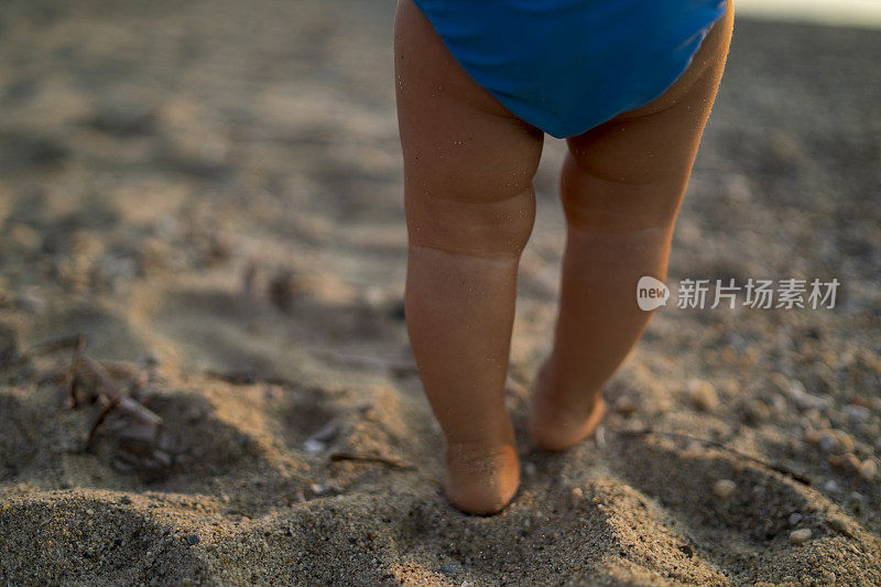 夏天在沙滩上走路的婴儿脚
