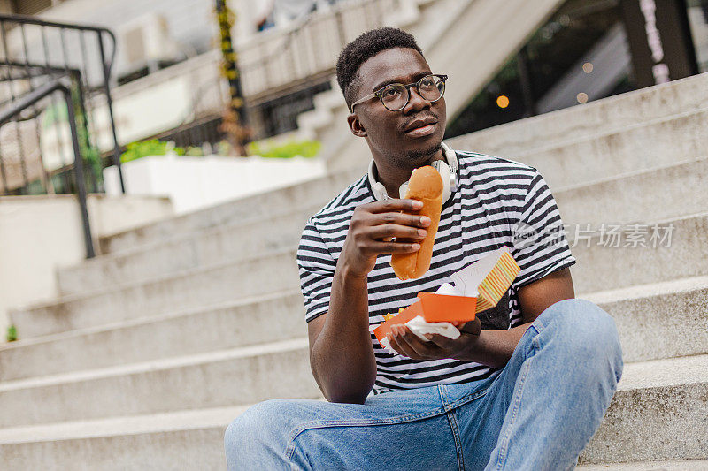 年轻的非洲裔美国人正在街上吃热狗