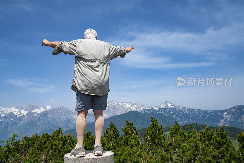 老男人的背影，站在柱子上伸开双臂站在陆地的顶端