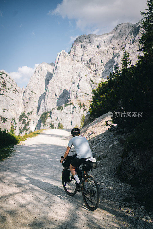 一个年轻人沿着阳光明媚的山路骑自行车