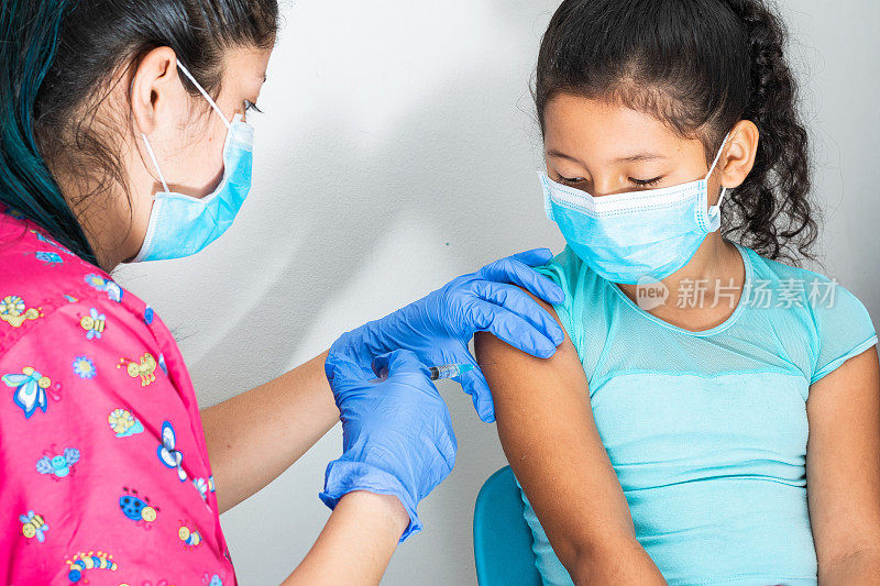 儿童护士在给棕色女孩的手臂注射。(8岁女童)，医生手戴橡胶手套注射COVID-19疫苗。流感疫苗。医学概念，健康和流行病。