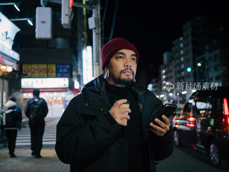 年轻的亚洲男子在东京等出租车或优步在晚上。