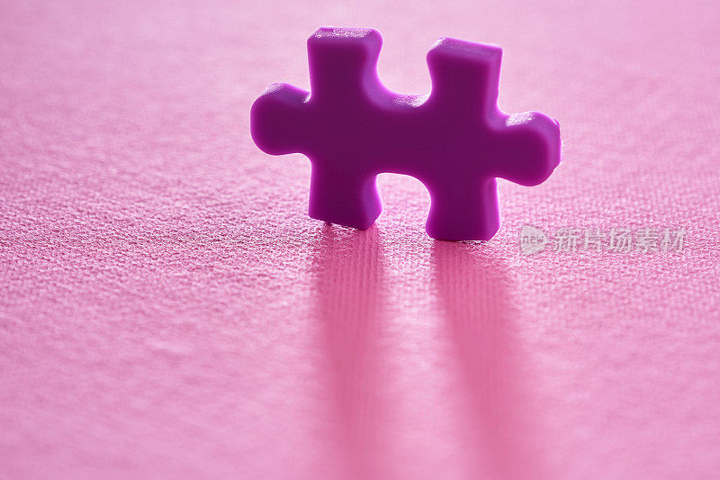 粉色背景上的紫色拼图的特写