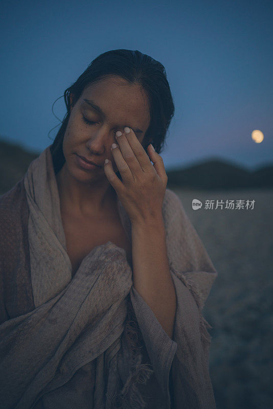 黄昏时，裹着毛巾的年轻妇女在海滩上放松