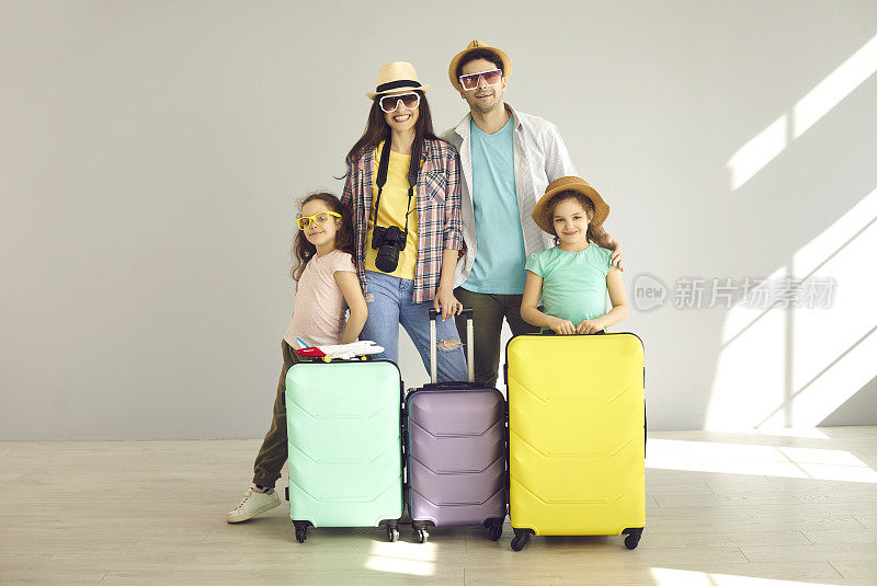 一个家庭的肖像与行李站在一个明亮的房间，准备去暑假。