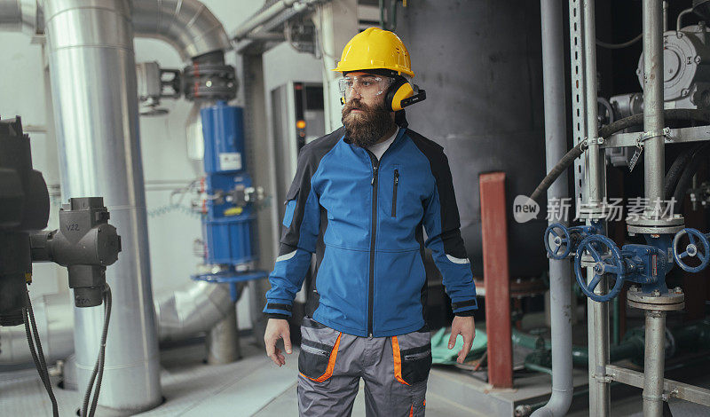 一名穿着制服的采暖工人站在采暖厂内。