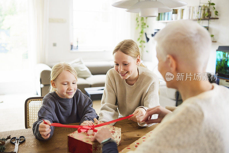 两个女儿在家里和母亲一起拆开圣诞礼物