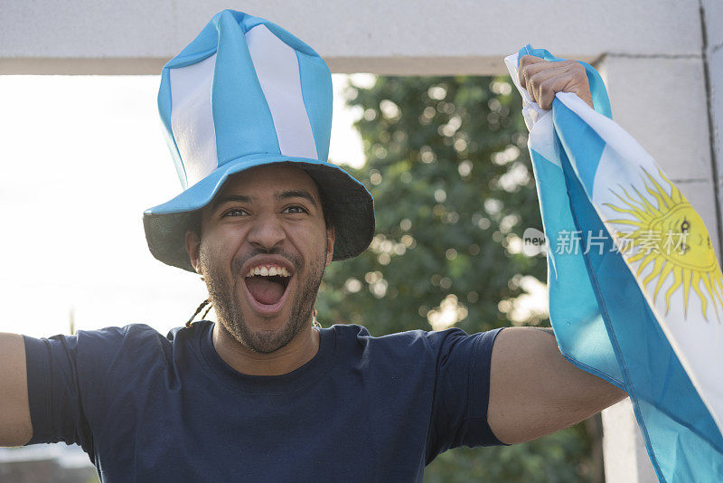 幸福的阿根廷人的肖像与帽子和国旗庆祝在世界杯期间的一粒进球