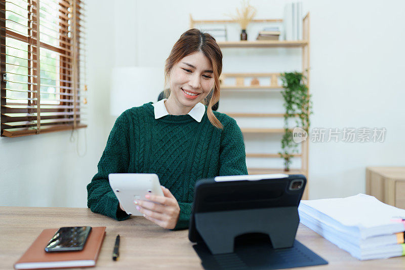 企业主或亚洲女性营销人员在办公室工作中使用计算器和平板电脑