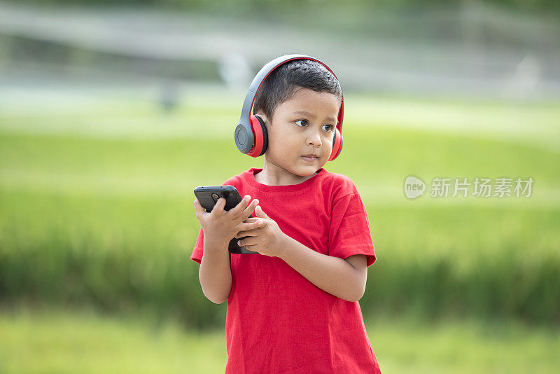 蹒跚学步的男孩用耳机听音乐