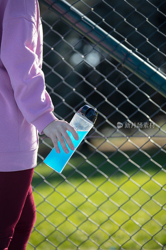 年轻女子在篮球场上进行户外运动时正在补水。