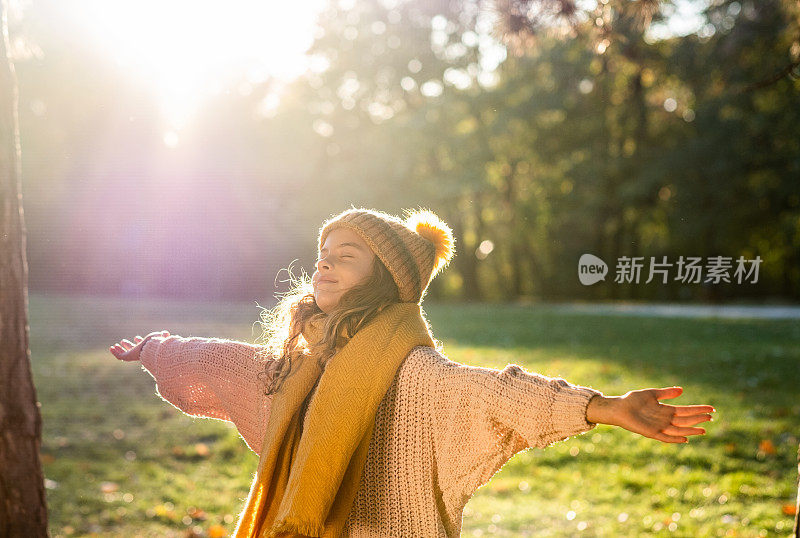 一个十几岁的女孩在公园里张开双臂的肖像。