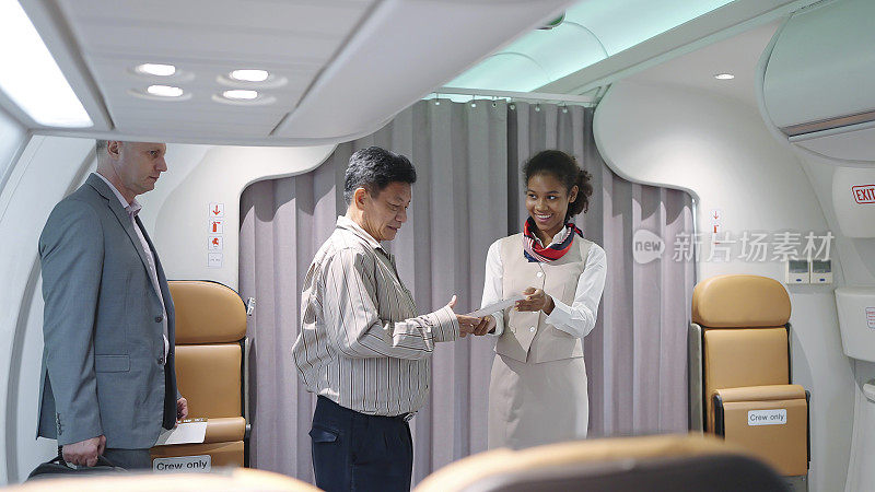 穿着制服的年轻女乘务员站在飞机入口，微笑着检查乘客的登机牌，欢迎乘坐这架航班。航空公司运输
