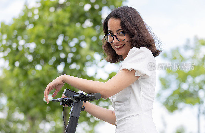 一位年轻女子在公园里骑着电动滑板车。