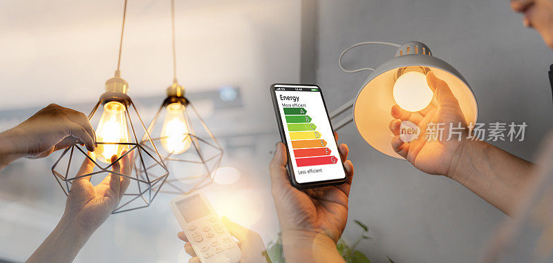男人换一个新的电灯泡，用手遥控开26度空调让家里更节能。家电节能。