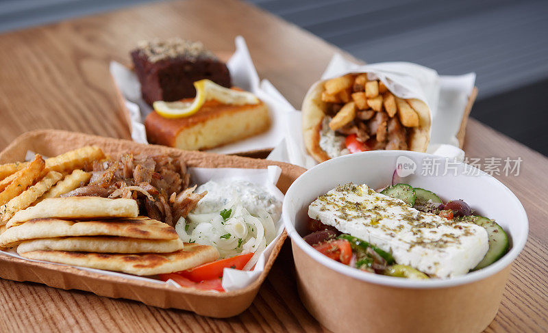 传统的希腊快餐用可回收的纸餐具盛着。皮塔羊肉串肉，薯条，白酸奶酱和新鲜沙拉准备午餐