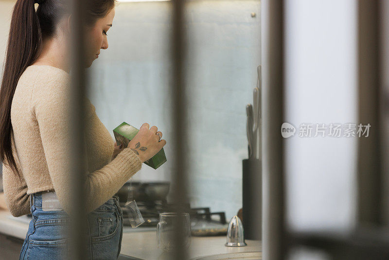 迷人的年轻女子正在家庭厨房里点菜，手洗杯子和盘子。