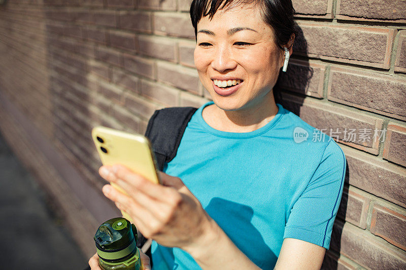 一名年轻的日本女子在健身后使用智能手机休息