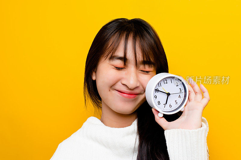 人和时间。女孩和他的白色闹钟。时间的重要性在生活中所花费的时间的价值，在工作中的时间观念和准时性