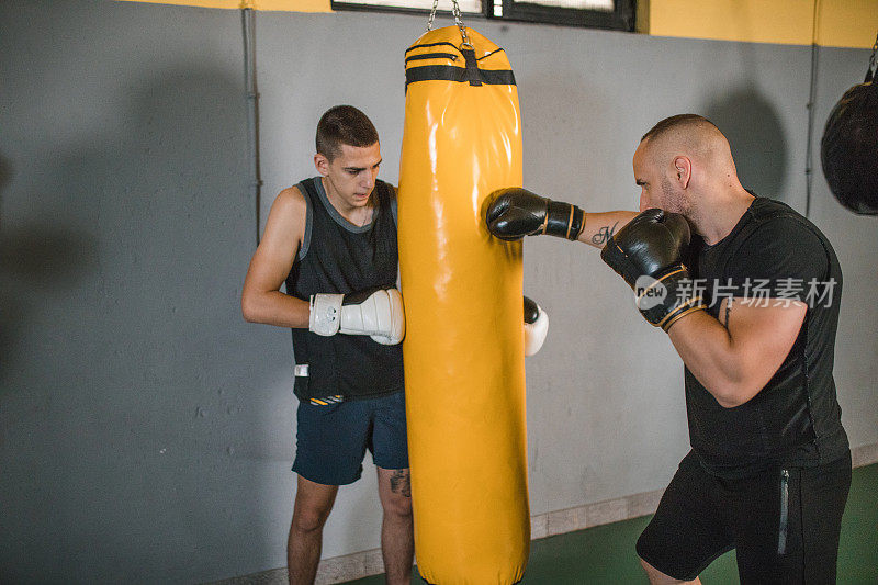 一个强壮的拳击手在健身房和他的拳击手朋友一起训练。拳击运动员为拳击比赛、比赛或比赛做准备的人