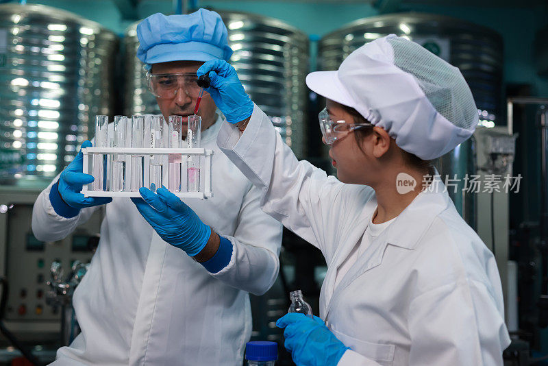 几个实验室技术人员在做水分析，穿着无菌防护设备。饮用水生产。