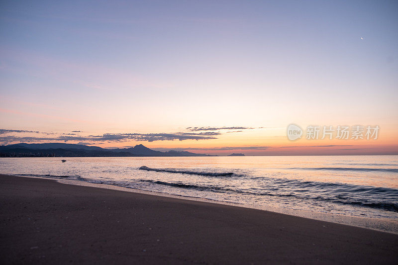 海景。清晨在海滩上冲浪。背景是群山……