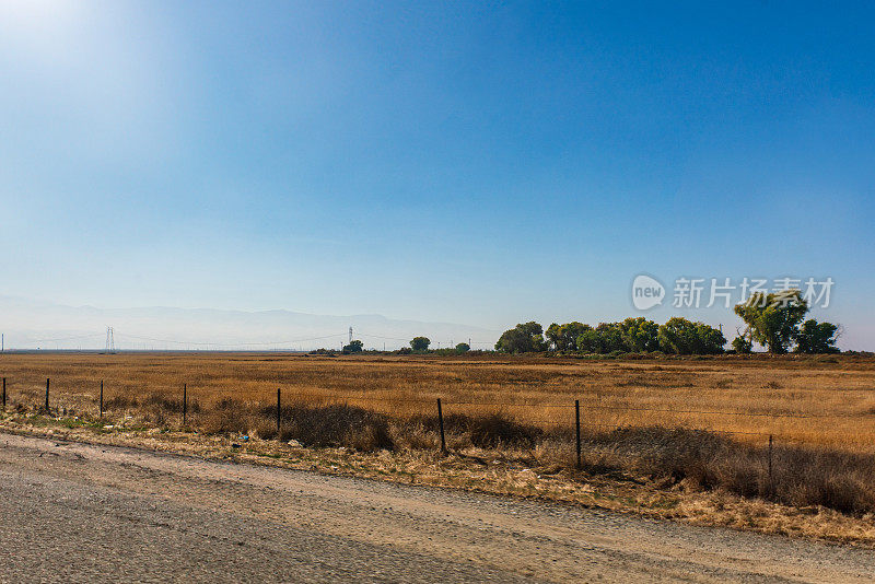 加州99号公路旁的农田，背景是山脉和湛蓝的天空