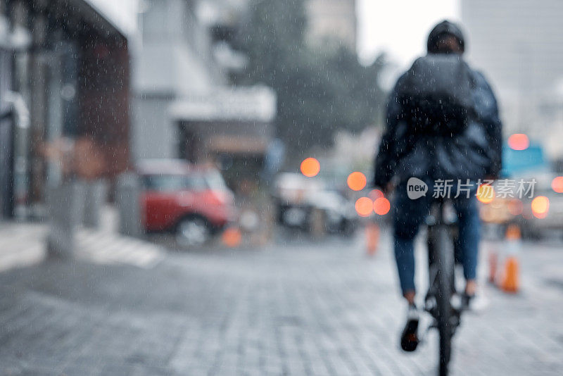 骑自行车的人，在雨天或寒冷的天气里在城市里骑自行车和送货。骑自行车的人冒雨带着货物，在市区街道上运输或派送快递服务