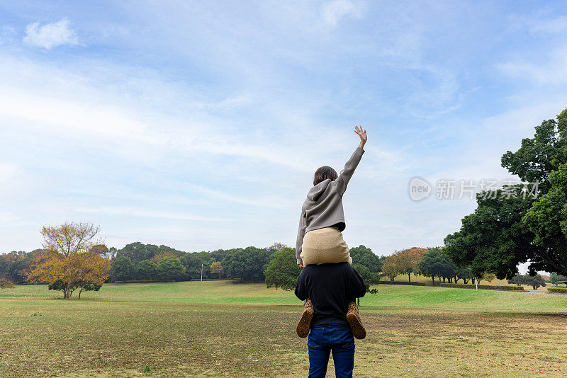 一对夫妇在公园里，丈夫把妻子扛在肩上