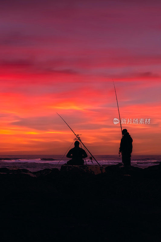 两个人海上钓鱼的剪影与惊人的日落和海上的云景