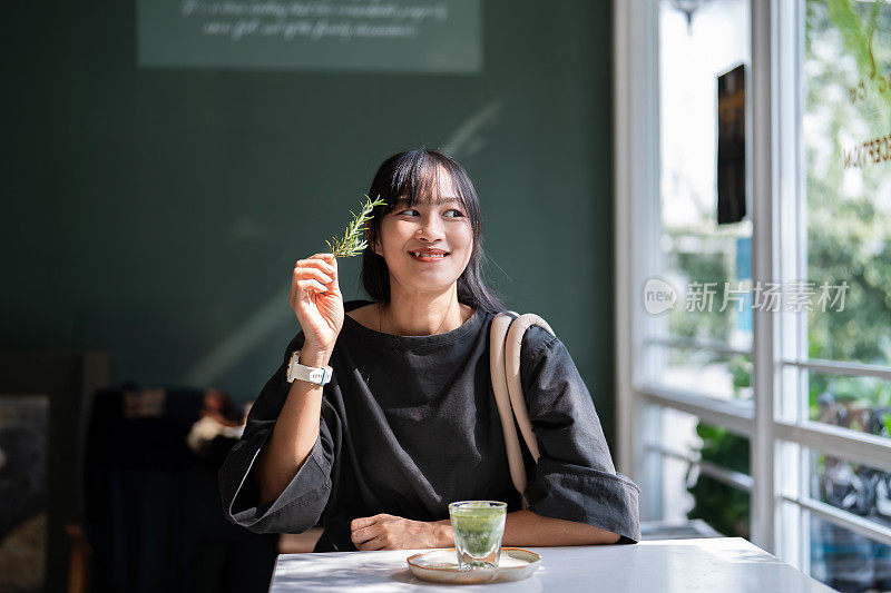 亚洲女性在现代咖啡馆品尝热腾腾的抹茶绿茶，呼吸迷迭香。