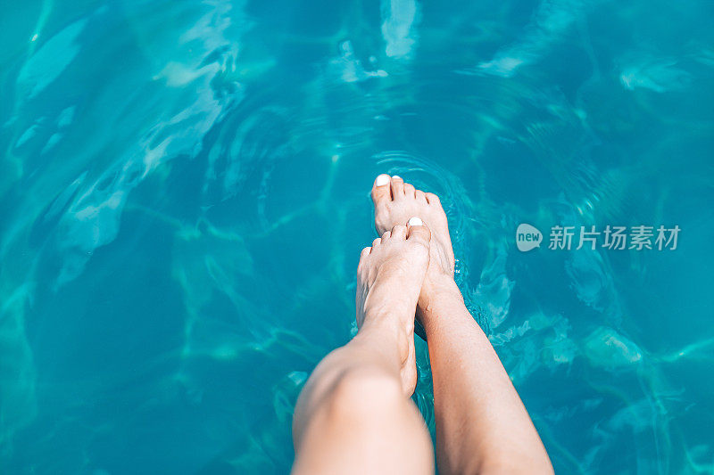 细长的女性腿在品尝水。暑期休息和假期的概念。带有复制空间的背景。