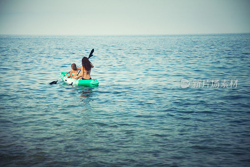 一个女人和一个小女孩在海上划着皮艇