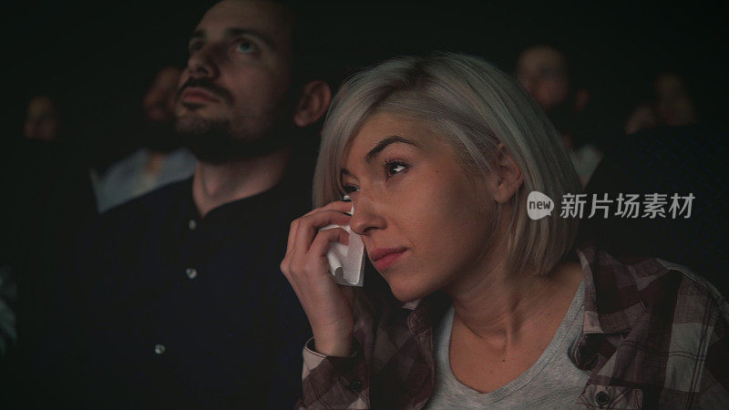 女人在电影院看电影时哭泣
