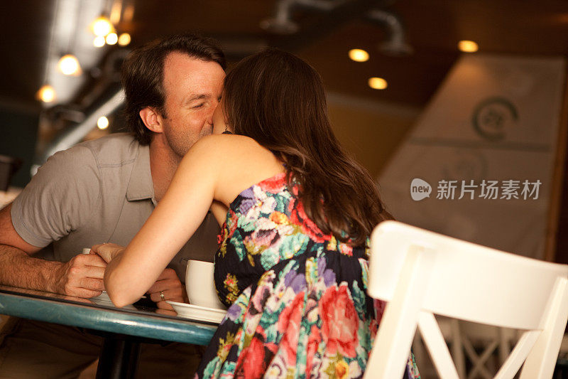 快乐的年轻情侣在咖啡馆里互相亲吻