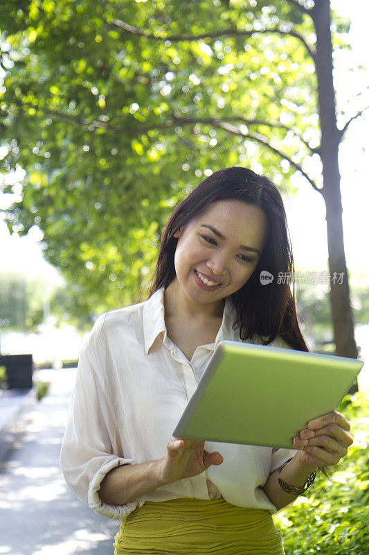 迷人的亚洲华裔女商人在户外使用数码平板电脑