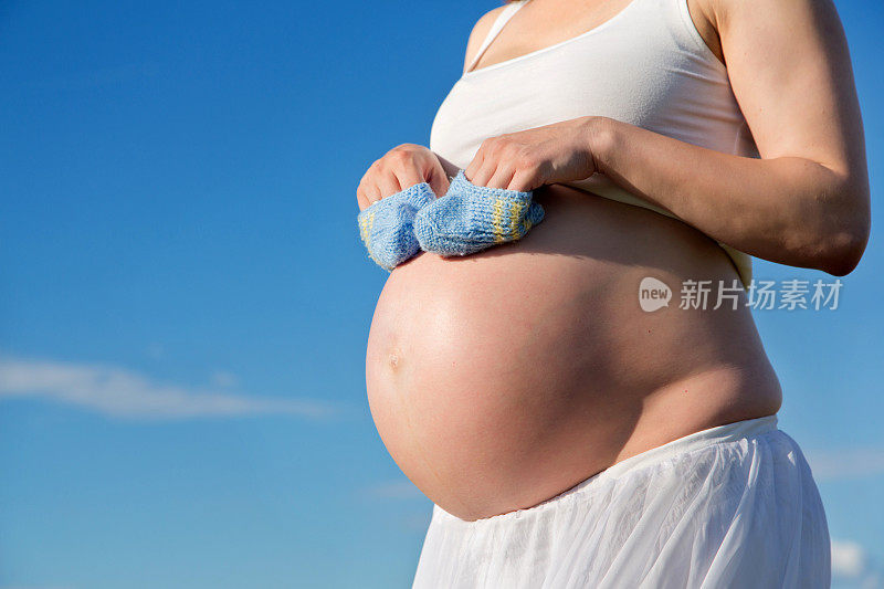 孕妇抱着婴儿鞋的特写