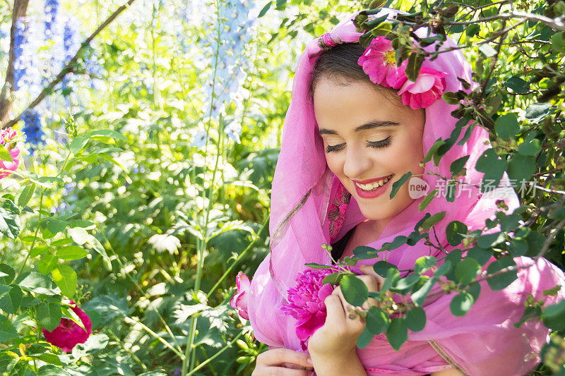 笑着15岁戴着粉红色的围巾，在明亮的花园里