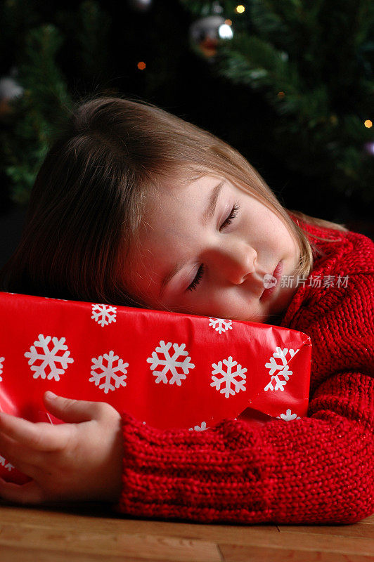 小女孩在圣诞树旁的圣诞礼物上熟睡
