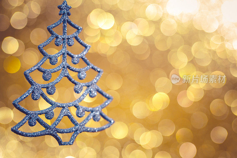 闪亮的蓝色圣诞树在散焦的金色背景