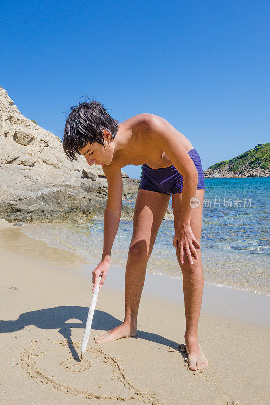 小男孩在沙滩上画画