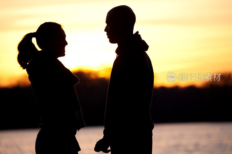 黎明时分，一对夫妇在湖边的剪影